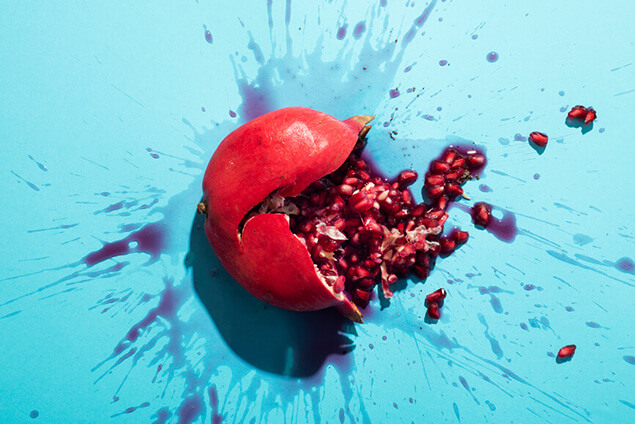 Aufgeplatzter Granatapfel in rot vor blauem Hintergrund